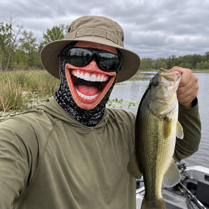 Grinwear Belly Laugh funny face balaclava worn on a bass boat holding a largemouth bass